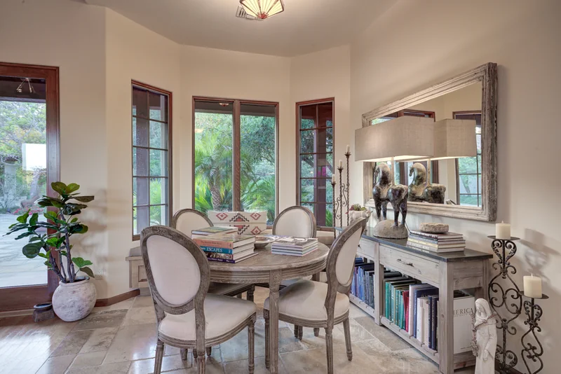 Formal dining room with upholstered chairs and garden-facing doors.