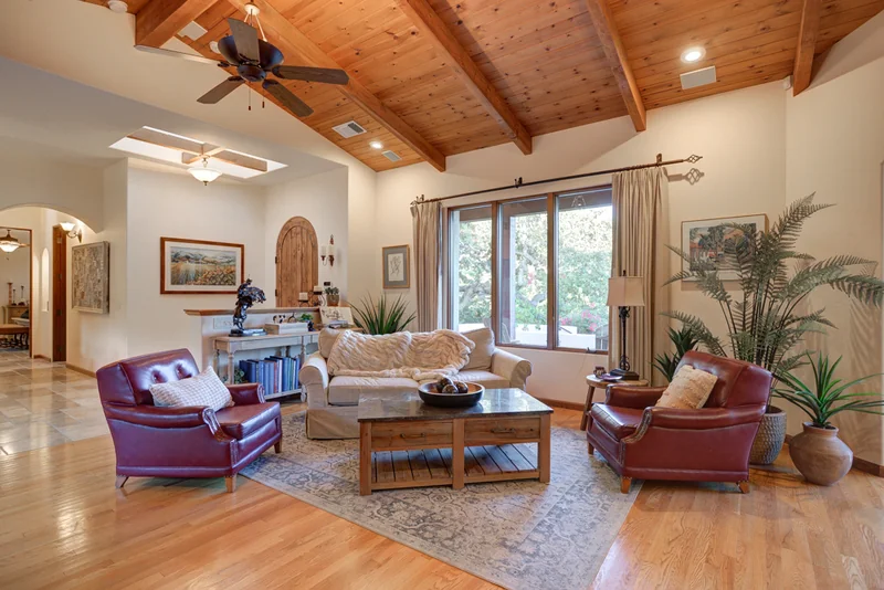 Living room beneath a wood ceiling with large garden-facing windows.