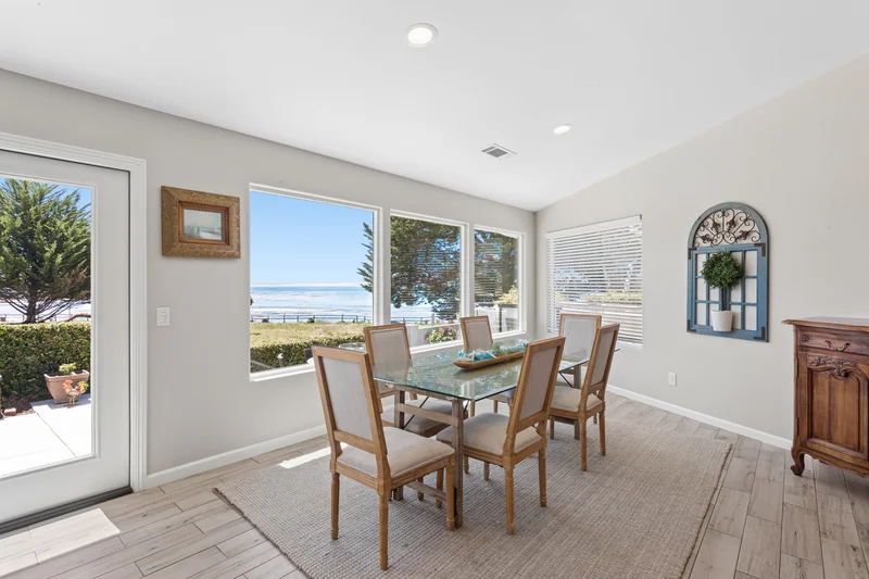 Dining table beside windows overlooking the coastal garden.