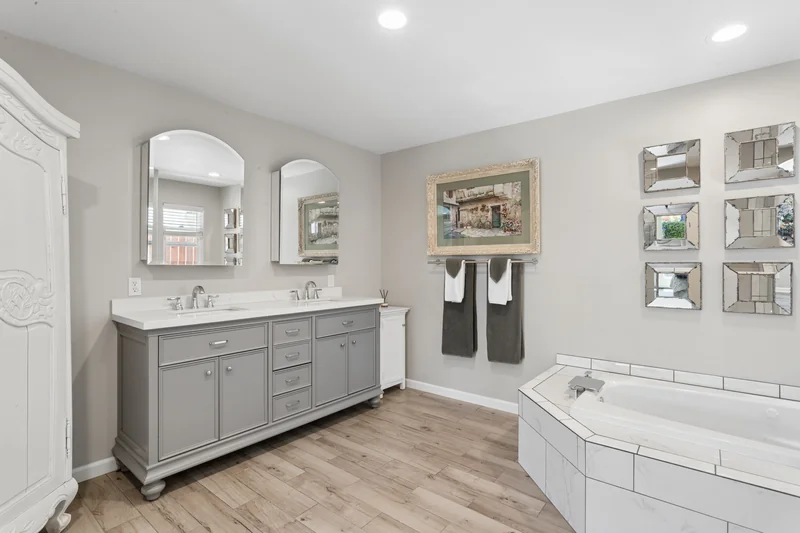 White bathroom with double vanity and glass shower enclosure.