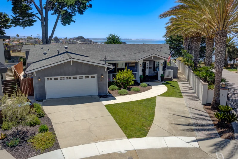 Elevated front view of a coastal home framed by palm trees.