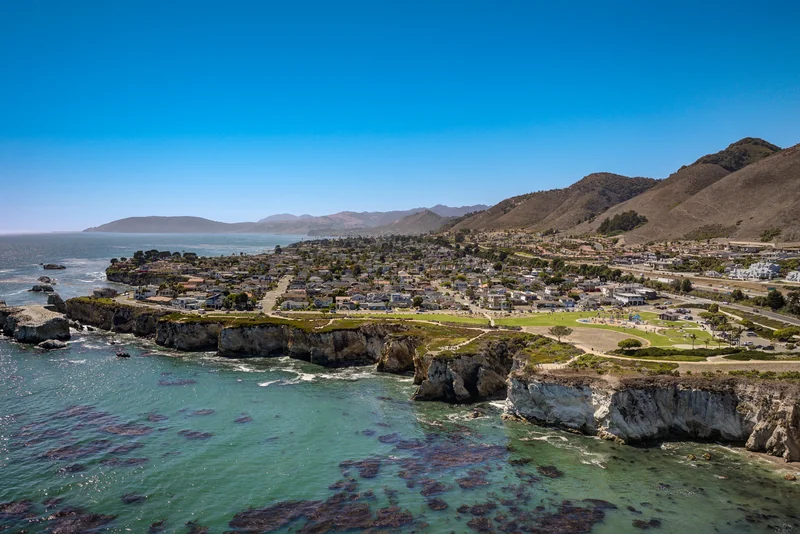 Wide coastal aerial showing turquoise water and a rocky shoreline.