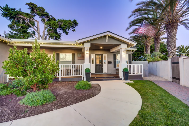 Front entrance and garden with warm lights at twilight.
