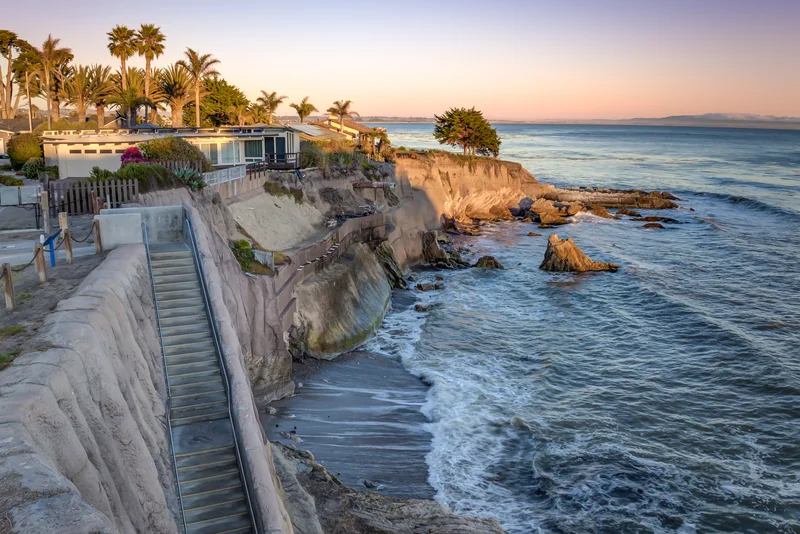 Sunset view along rocky coastal bluffs and oceanfront homes.