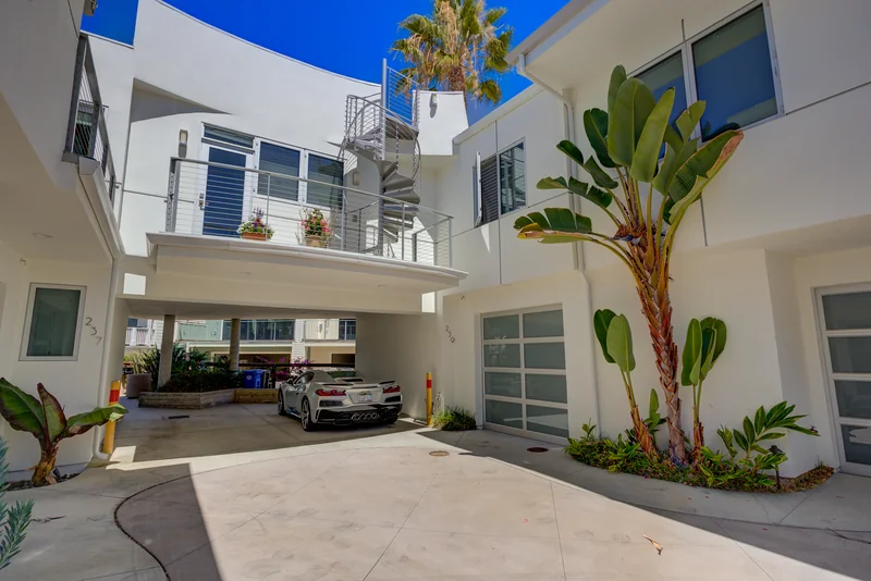 White multi-story home with an open garage and planted entrance.