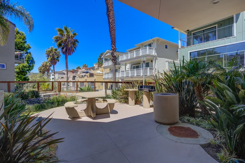 Sunny outdoor seating terrace beside a white coastal home.