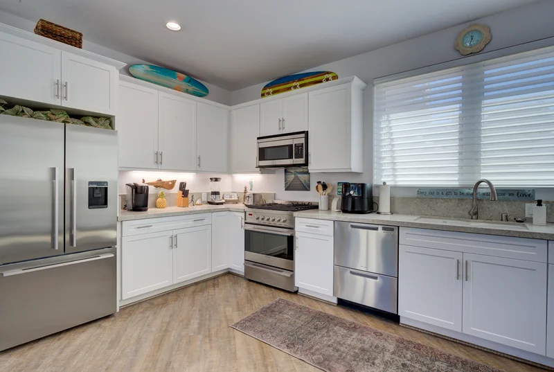 White kitchen with stainless steel appliances and recessed lighting.