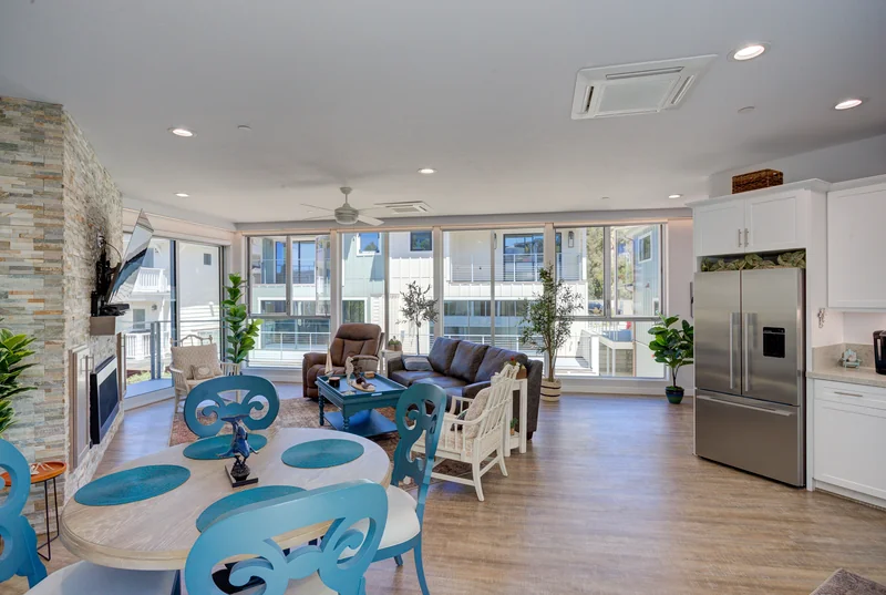 Blue dining chairs beneath a chandelier beside the living room.