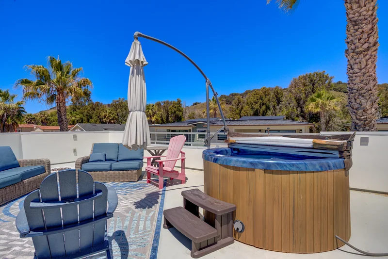 Rooftop deck with lounge seating, umbrella and hot tub.