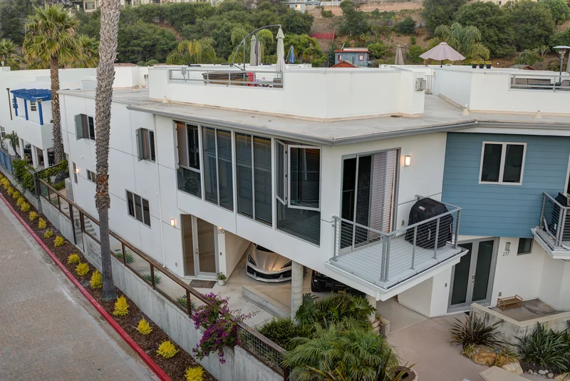 Elevated view of a white coastal home with a rooftop terrace.
