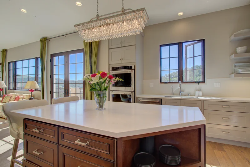 White kitchen with a dark wood island and garden-facing windows.