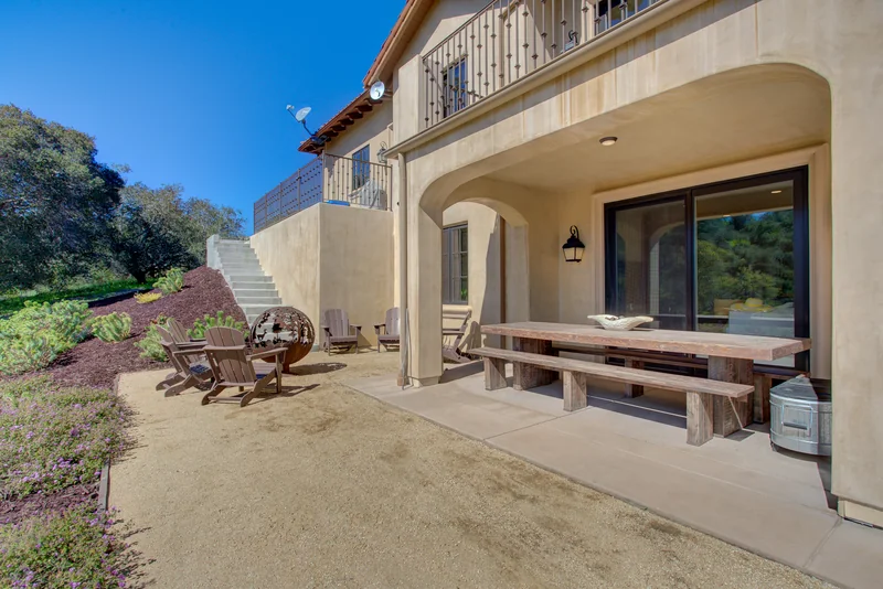 Covered outdoor dining area beside a landscaped hillside.
