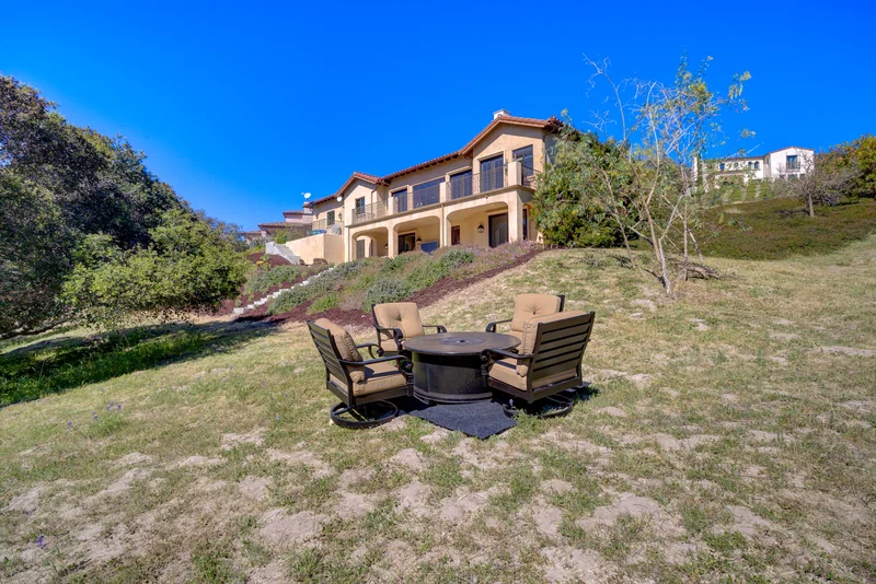 Hillside garden seating beneath a two-story home.
