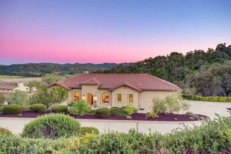 Front entrance and curved driveway beneath a pink evening sky.