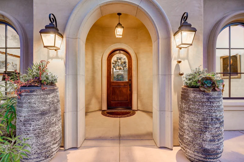 Arched front doorway framed by stone columns at dusk.