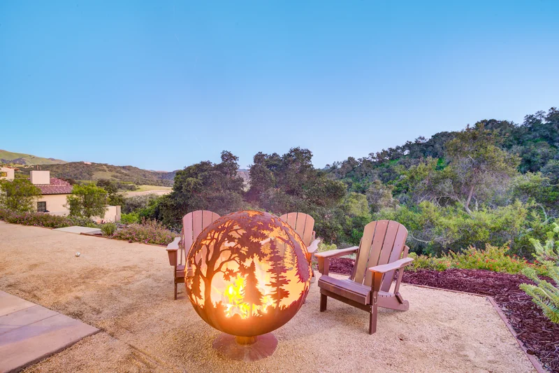 Sculptural fire globe and outdoor chairs at twilight.