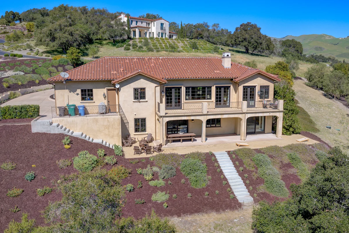 Elevated rear view of a hillside home and landscaped terraces.